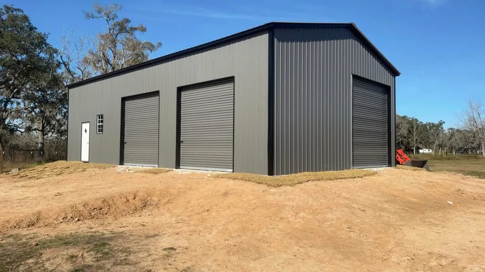 Completed dark metal building with three roll-up doors