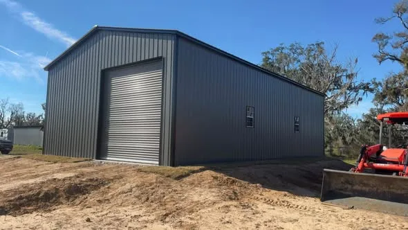 Dark metal building viewed from the side with a red tractor